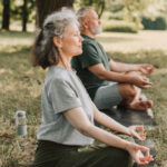 elderly man and woman meditating in a park