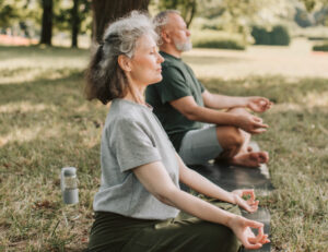 elderly man and woman meditating in a park