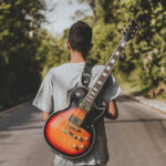 teen boy standing with a guitar on his back