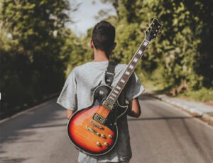 teen boy standing with a guitar on his back